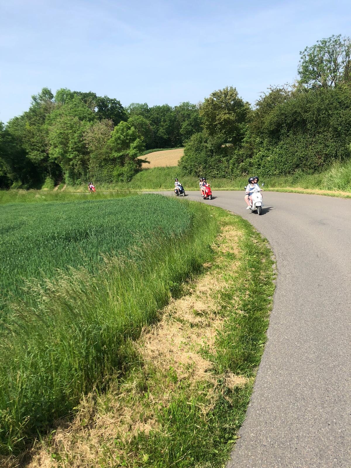 Vespa rijders door een pittoresk Ardens dorpje met stenen huizen